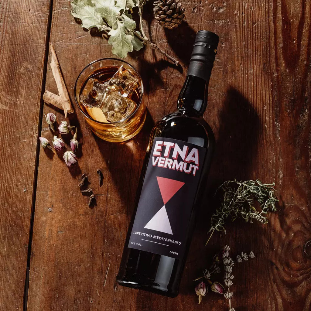 Etna Vermut, Flasche liegend auf einem Holztisch fotografiert mit einem Glas und Deko
