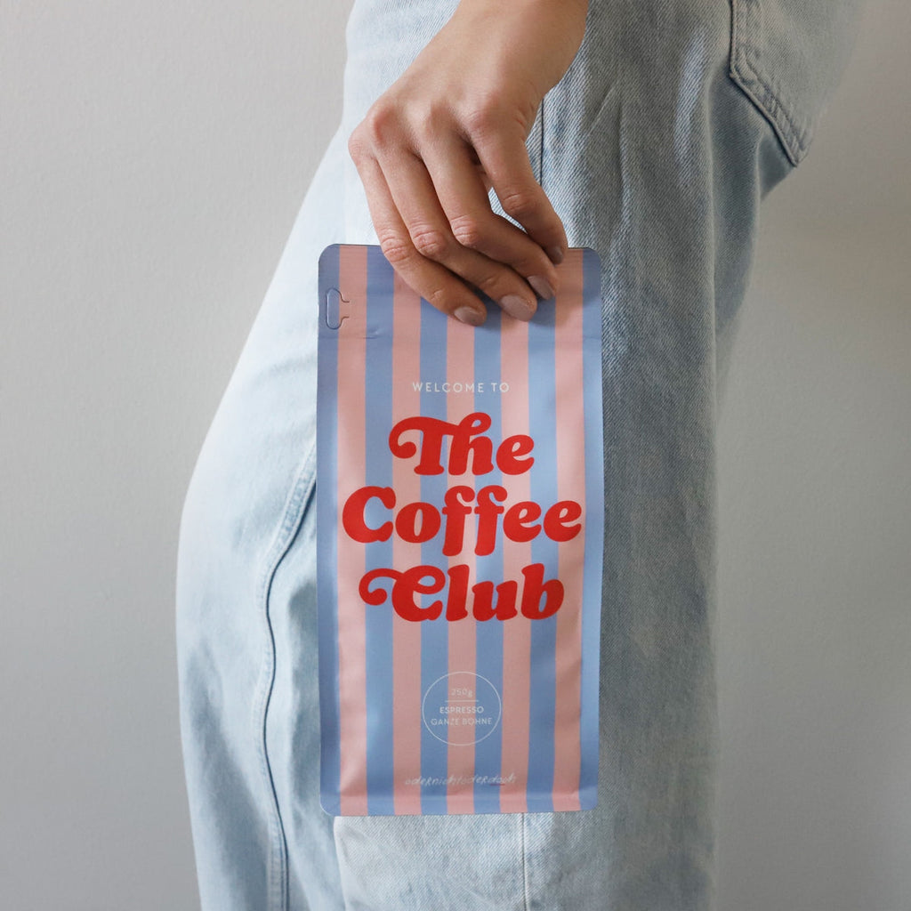 The Coffee Club X Kaffee Ganze Bohne, 250g in der Hand eines Models