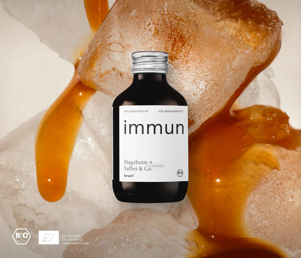 Immun X Oxymel, übergroße Eiswürfel im Hintergrund, über die eine braune Flüssigkeit fließt