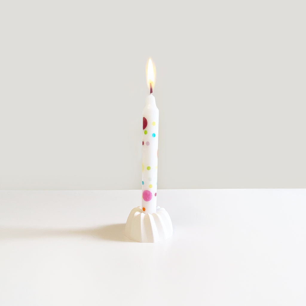 Konfettikerze, brennend auf einem Gugelhupf-Kerzenständer