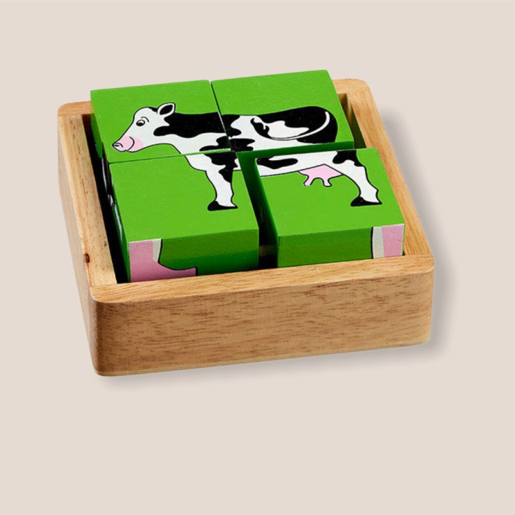 Blockpuzzle, vier Würfel, die zusammen ein Bild ergeben, hier eine Kuh, Hintergrundfarbe grün, in einer braunen Holzbox