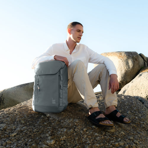 Basalt Monochrome X Pro Pack, ein Model sitz auf einem Berg, der Rucksack steht neben ihm