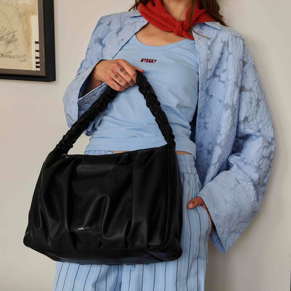 Faltentasche x Schwarz, gehalten von einem Model