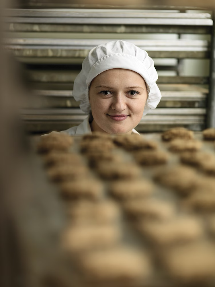 Eine Frau mit Haarnetz bei der Keksproduktion
