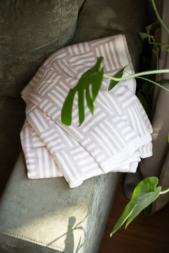 Ecru-Leinen X Dash Plaid Kuscheldecke, auf einer grünen Couch