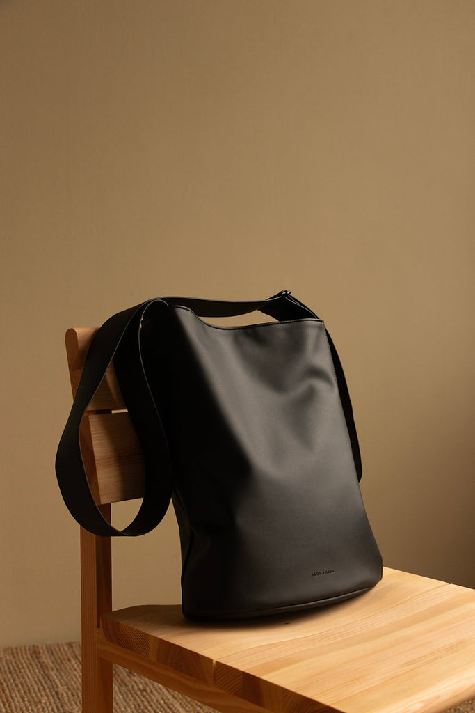 Naomi X Shopper Handtasche, auf einem Holzstuhl vor hellbrauner Wand