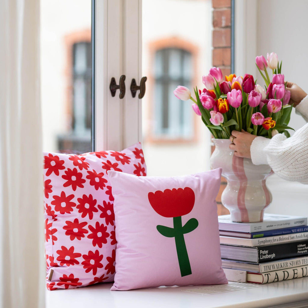 Mehrere Kissen in rosa mit rot, dekoriert mit Blumen an einer Fensterbank